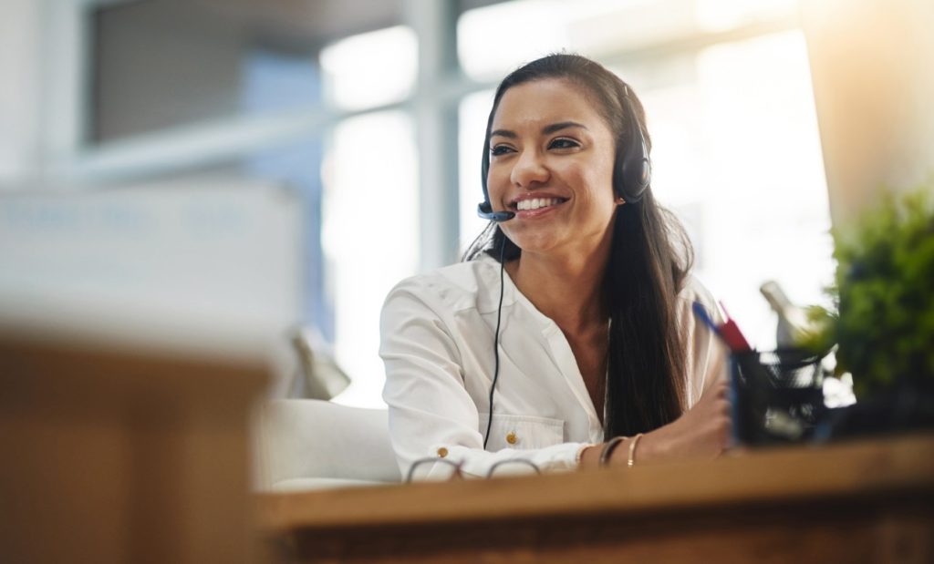 Happy woman sitting at desk smiling with headset