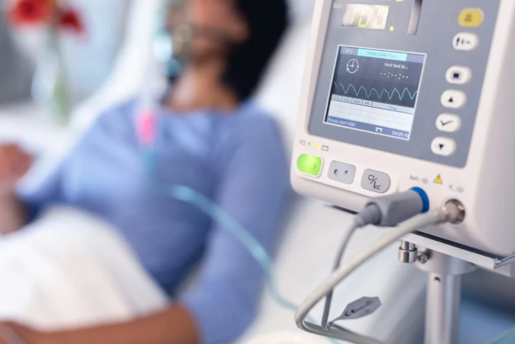 Blurred woman in hospital bed in background with heart monitor
