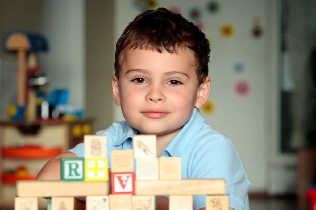 Small child playing with blocks and smiling at camera
