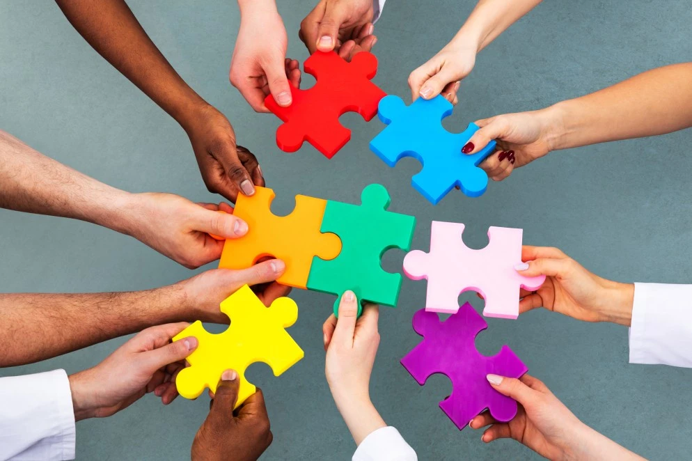 Join the BrightSide Assist team: Multicultural hands holding puzzle pieces
